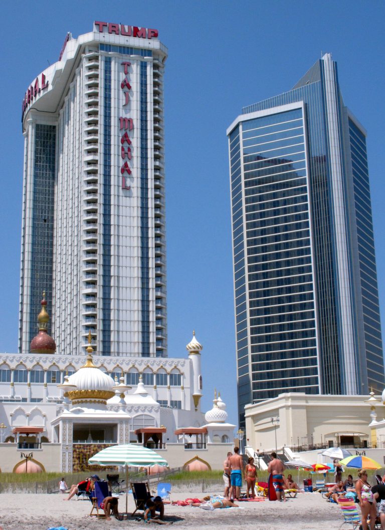 In this photo taken on July 23, 2014, beachgoers enjoy the sand in front of the Trump Taj Mahal Casino Resort,rear left, in Atlantic City N.J. The casino's parent company, Trump Entertainment Resorts, filed for bankruptcy on Sept. 9, 2014 and a Pennsylvania company that maintains its fire alarms and sprinkler systems wants a Delaware judge to let it end its contract with the casino, claiming it hasn't been paid more than $250,000. (AP Photo/Wayne Parry)