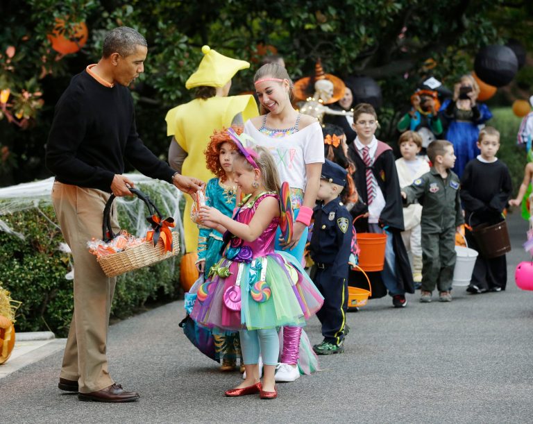 President Barack Obama hands out Halloween treats as he welcomes local children and children of military families to 'trick-or-treat' on the South Lawn of the White House in Washington, Thursday, Oct. 31, 2013. The White House canceled its Halloween celebration last year in aftermath of Superstorm Sandy. (AP Photo/Pablo Martinez Monsivais)
