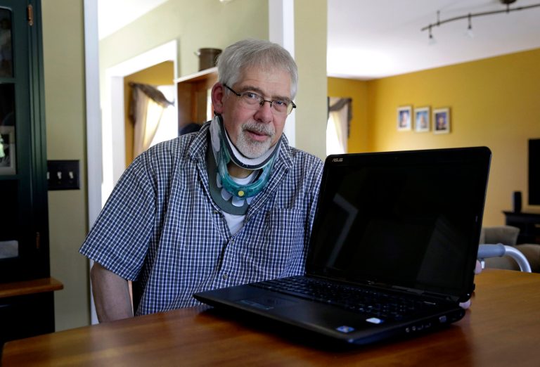 This photo taken May 8, 2014 shows Mark Matulaitis posing with his laptop that he uses for virtual house calls with his neurologist in his home in Salisbury, Md. Matulaitis has had Parkinson's disease since 2011 and sees a neurologist at the University of Rochester via his laptop and special Skype-like software.  (AP Photo/Patrick Semansky)