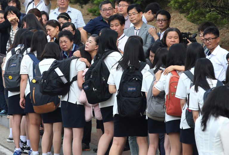 Students who survived the sinking of a ferry Sewol are comforted by parents of their friends who lost their lives in the disaster as they make their way back for their first class since the disaster in Ansan, South Korea, Wednesday, June 25, 2014. As parents of the dead wept, more than 70 teenagers who survived the ferry sinking that killed hundreds of their schoolmates walked in a somber procession Wednesday to their first classes since the April disaster. (AP Photo/Yonhap)  KOREA OUT