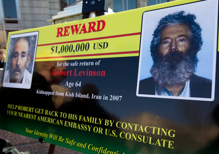 An FBI poster showing a composite image of  former FBI agent Robert Levinson, right, of how he would look like now after five years in captivity, and an image, left, taken from the video, released by his kidnappers, Tuesday, March 6, 2012, in Washington during a news conference.  (AP Photo/Manuel Balce Ceneta)