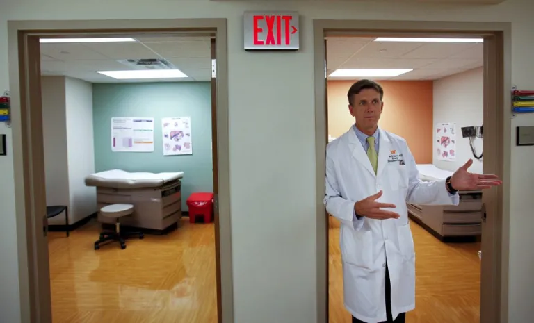 A doctor in a lab coat outside an exam room