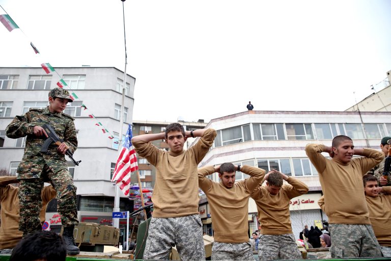 In this Thursday, Feb. 11, 2016 photo, members of Iranian Basij paramilitary force re-enact the January capture of U.S sailors by the Revolutionary Guard in the Persian Gulf, in a rally commemorating the 37th anniversary of Islamic Revolution in Tehran, Iran The nationwide rallies commemorate Feb. 11, 1979, when followers of Ayatollah Khomeini ousted U.S.-backed Shah Mohammad Reza Pahlavi. (AP Photo/Ebrahim Noroozi)
