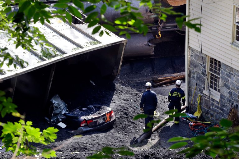 Officials walk past a car that was destroyed by a CSX freight train that derailed while hauling coal  in Ellicott City. (AP Photo)
