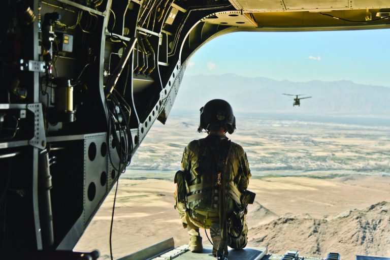 U.S. Army Sgt. Spencer Helmick, a 15U CH-47 helicopter repairer, assigned to Task Force Shadow observes the terrain and air space of Afghanistan during a flight operation Oct 14 2018. As a CH-47 crew chief Helmick is responsible for air surveillance and attending to any in-flight maintenance.