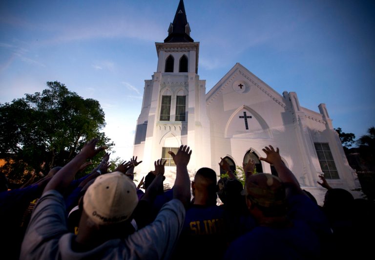 The men of Omega Psi Phi Fraternity Inc. lead a crowd of people in prayer outside the Emanuel AME Church, Friday, June 19, 2015, after a memorial in Charleston, S.C. (AP Photo/Stephen B. Morton)