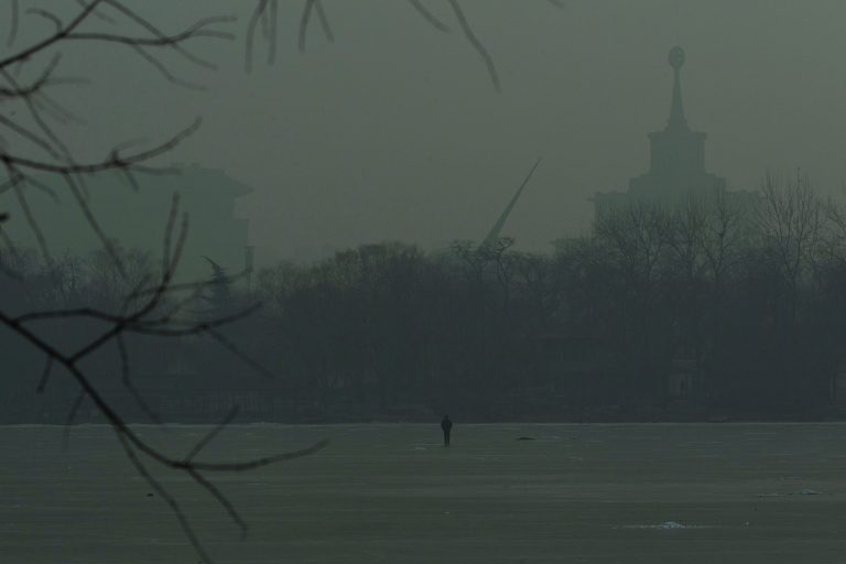 A man walks on an frozen lake on a hazy day in Beijing, China, Monday, Jan. 14, 2013. Beijing schools kept children indoors and hospitals saw a spike in respiratory cases Monday following a weekend of off-the charts pollution in China's smoggy capital, the worst since the government began being more open about air-quality data. (AP Photo/Alexander F. Yuan)