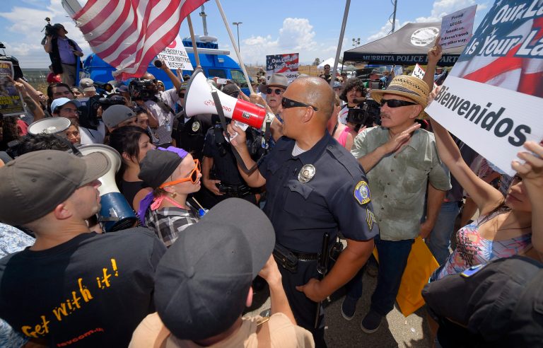 A Murrieta police sergeant talks to demonstrators as they confront each other Friday outside a U.S. Border Patrol station in Murrieta, Calif. (AP/Mark J. Terrill)