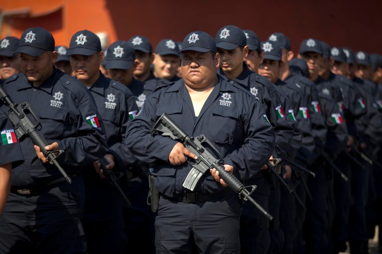 Self-defense group members stand in their new uniforms before the start of a ceremony in Tepalcatepec, Mexico, Saturday, May 10, 2014. At the ceremony in the town where the vigilante movement began in February 2013, officials handed out new pistols, rifles and uniforms to 120 self-defense group members who were sworn into a new official rural police force. Mexico's government on Saturday began demobilizing the vigilante movement of assault-rifle-wielding ranchers and farmers that had succeeded in largely expelling the Knights Templar cartel from the western state of Michoacan when authorities couldn't. (AP Photo/Eduardo Verdugo)