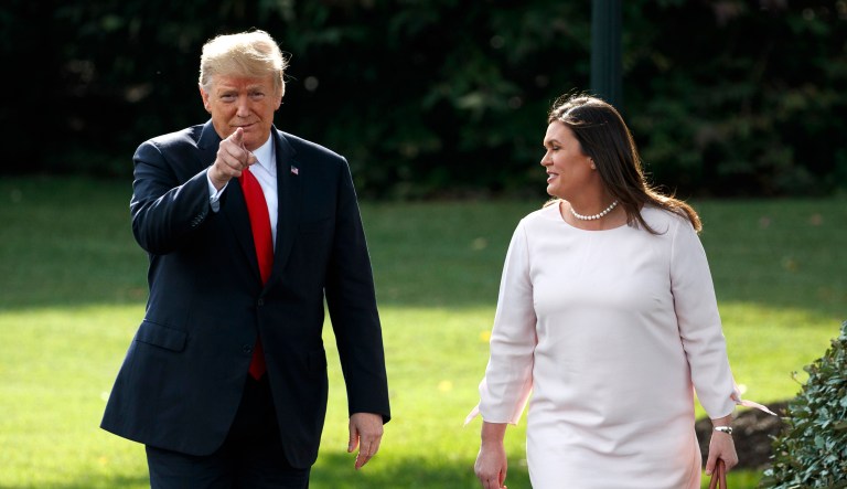 President Donald Trump walks with White House press secretary Sarah Huckabee Sanders to speak with reporters on the South Lawn of the White House, Tuesday, Oct. 9, 2018, in Washington.