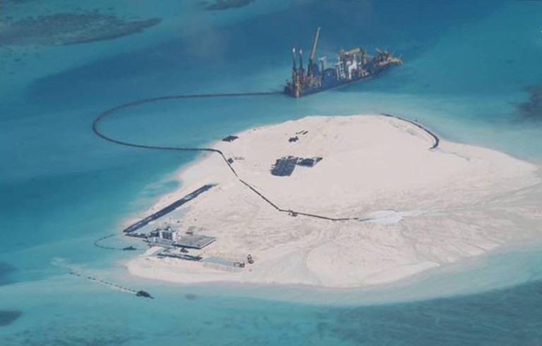 FILE - In this Feb. 25, 2014 file photo taken by surveillance planes and released May 15 by the Philippine Department of Foreign Affairs, a Chinese vessel, top center, is used to expand structures and land on the Johnson Reef, called Mabini by the Philippines and Chigua by China, at the Spratly Islands in the South China Sea, Philippines. The Philippines wants an international tribunal to issue a decision as quickly as it can on a Manila complaint that questions the legality of China's massive territorial claims in the South China Sea because the disputes continue to escalate. Foreign Secretary Albert del Rosario said late Tuesday, June 17 that the Philippines would ask its lawyers to petition the Arbitral Tribunal in the Hague, the Netherlands, to issue an earlier ruling after China said it would not get involved in the case, which should shorten the arbitration proceedings. (AP Photo/Philippine Department of Foreign Affairs, File)