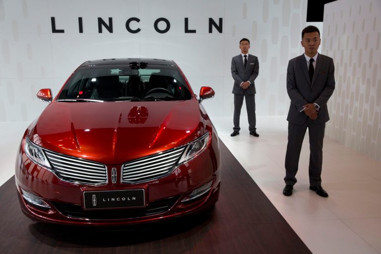 Staff members stand near a Lincoln MKZ Sedan on display during a press event in Beijing, China, Thursday, April 17, 2014. Ford Motor Co. says it will introduce its high-end Lincoln brand to China later this year with plans to open eight dealerships in seven cities. Lincoln is a late comer to China's luxury car market but Robert Parker, president of Lincoln China, said Thursday the brand is being introduced here after much deliberation and research. (AP Photo/Ng Han Guan)