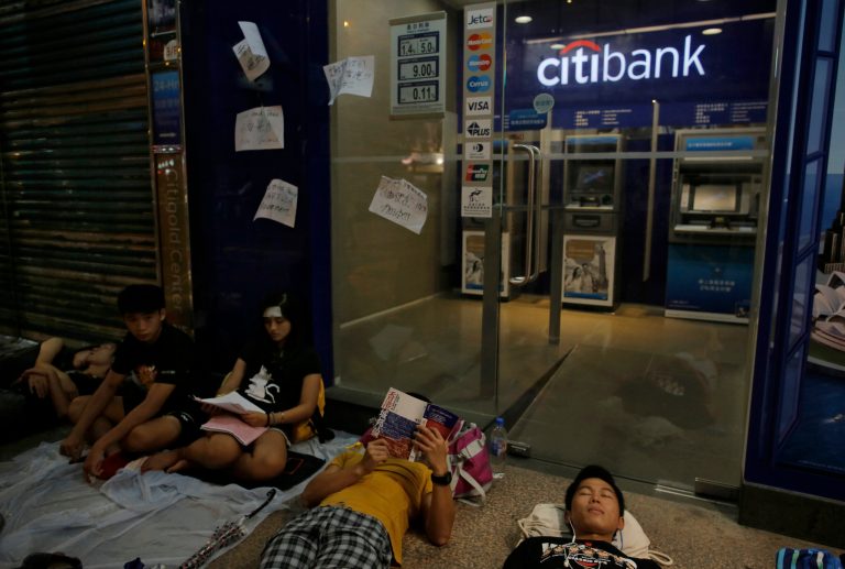 Protesters rest outside a shopping mall during a rally in Hong Kong, Thursday, Oct. 2, 2014. Shops in Hong Kong have closed and the local stock market has plunged but protesters are gambling their agitation for greater democracy will pay off by preserving institutions that made this former British colony a profitable asset to China. (AP Photo/Vincent Yu)