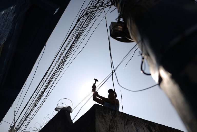 FILE - In this July 2, 2014 file photo, a man works on the rooftop of a home at the Providencia slum of Rio de Janeiro, Brazil. Brazil has slipped into recession, with government figures released Friday, Aug. 29, 2014 showing gross domestic product contracting for a second consecutive quarter. Brazil last experienced a recession between October 2008 and February 2009. (AP Photo/Leo Correa, File)