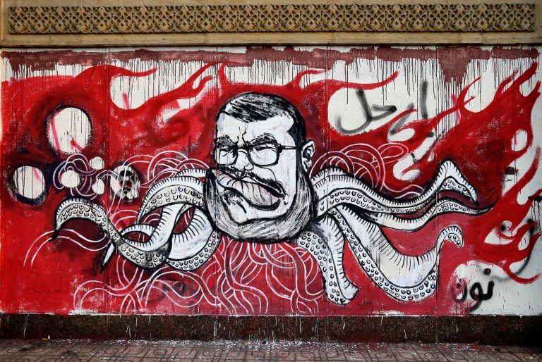   FILE - In this Saturday, Dec. 8, 2012 file photo, Graffiti depicting Egyptian President Mohamed Morsi covers an outer wall of the presidential palace in Cairo, Egypt. Some six months since becoming the first democratically elected president of Egypt, Morsi is widely accused of having abandoned pledges of inclusive government for doctrinaire and authoritarian ways. (AP Photo/Hassan Ammar, File)  