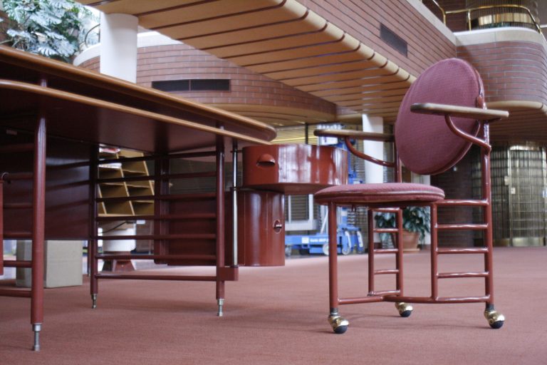 FILE - This Friday, April 18, 2014 file photo shows an original desk and a three-legged chair designed by architect Frank Lloyd Wright for workers at the SC Johnson Administration Building in Racine, Wis. A desk and chair designed by Frank Lloyd Wright has been returned to home products giant SC Johnson as part of a settlement with a California man who had planned to auction the distinctive and valuable furniture, a company spokesman said Tuesday. (AP Photo/M.L. Johnson, file)