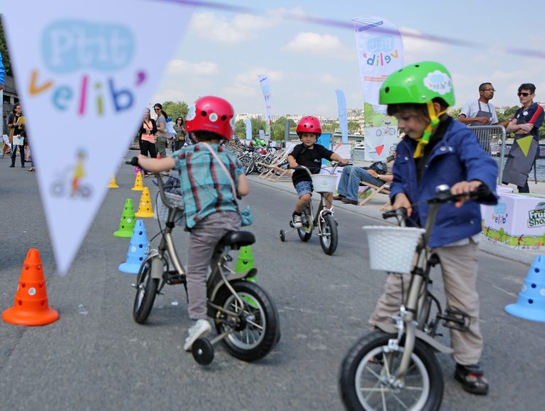 Children ride free bicycles as part of the Little Velib system experimented on the Seine river banks in Paris, Wednesday June 18, 2014.  Velib' is a system of free and low-cost public-transport bicycles organized by the Paris city government to help people move about the city by their own power.(AP Photo/Remy de la Mauviniere)