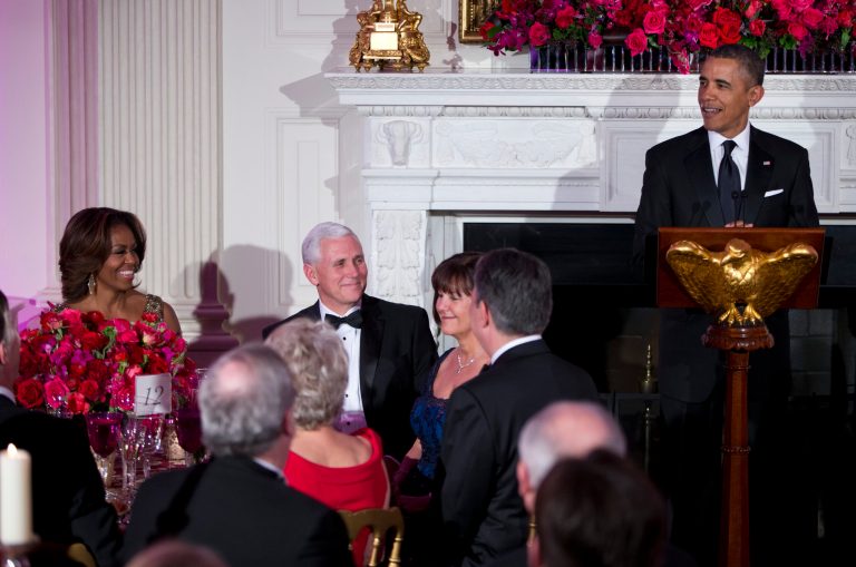 First lady Michelle Obama, left, and Gov. Mike Pence, R-Ind., center, look on as President Obama delivers remarks during a dinner for the National Governors Association in the state dining room of the White House on Sunday, Feb. 23, 2014, in Washington. (AP Photo/ Evan Vucci)
