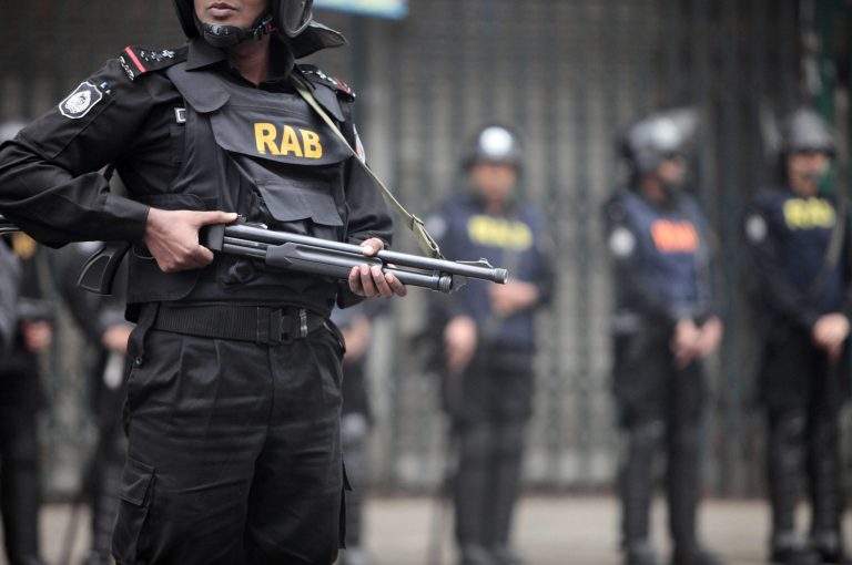   Members of Bangladesh Rapid Action Battalion (RAB) stand guard in front of opposition Bangladesh Nationalist party (BNP) office during a nationwide strike in Dhaka, Bangladesh, Tuesday, Dec. 11, 2012. Explosions of homemade bombs were reported across the Bangladeshi capital Tuesday as opposition activists enforcing a daylong general strike rioted and clashed with police. (AP Photo/ A.M. Ahad)  