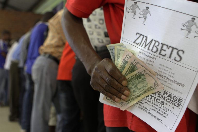 In this photo taken on Saturday, Jan. 18, 2014 a punter shows off his wins after betting on horses and football in Harare, Zimbabwe. Poor and desperate Zimbabweans hang out in Harare's crowded low-end betting halls, placing stakes as low as U.S. 20 cents on world soccer matches and international horse and dog races with fervent hopes of getting quick returns on their bit of cash (AP Photo/Tsvangirayi Mukwazhi)
