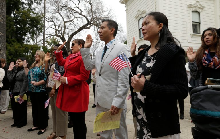 Mariasol Lota, second from the right, holds an American flag as she is sworn-in as a U.S. citizen during naturalization ceremonies at the Old Governor's Mansion in Sacramento, Calif., on Feb. 13. (AP Photo/Rich Pedroncelli)