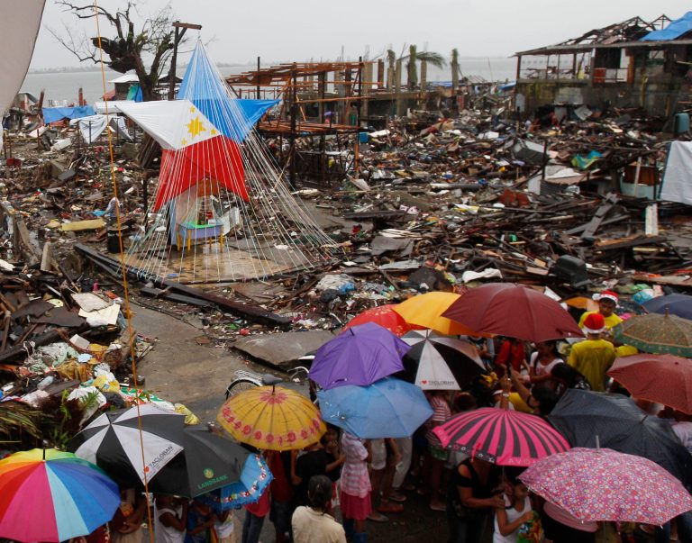 Children line up to receive a Christmas gift from volunteers near a giant lantern with the colors of the Philippine flag, in Tacloban, Philippines, a city devastated by the Nov. 8 typhoon Haiyan.  (AP Photo/Achmad Ibrahim)