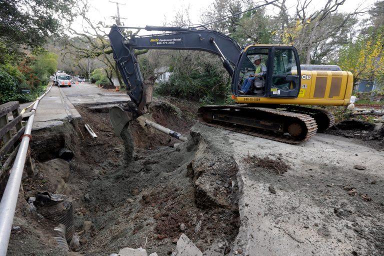   A worker from Pacific General Engineering works to clear the damage on the road caused by overflow water from Lafayette Creek in Lafayette, Calif., Tuesday, Dec. 4, 2012. Just as Northern California residents recovered from a series of wet, windy storms, another system on the way is expected to drench the area. (AP Photo/Marcio Jose Sanchez)  