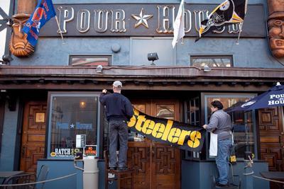 Jim Richards and Omar Garzion hang up a Steelers banner in front of the Pour House on Capitol Hill. The Pour House attracts Pittsburgh Steelers fans from originally from Pennsylvania during NFL season. In Washington, DC on Thursday, February 3, 2011.