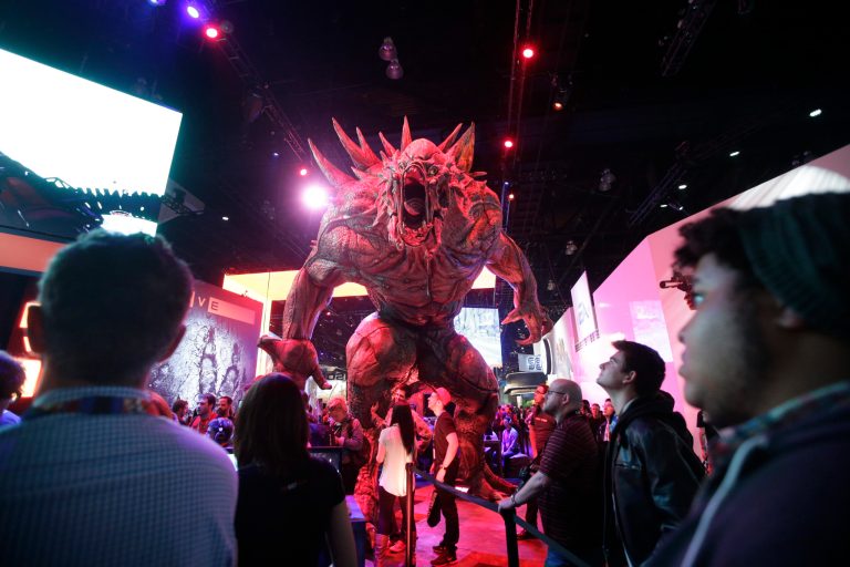 FILE - In this June 10, 2014 file photo, people stand next to a monster character from the video game 