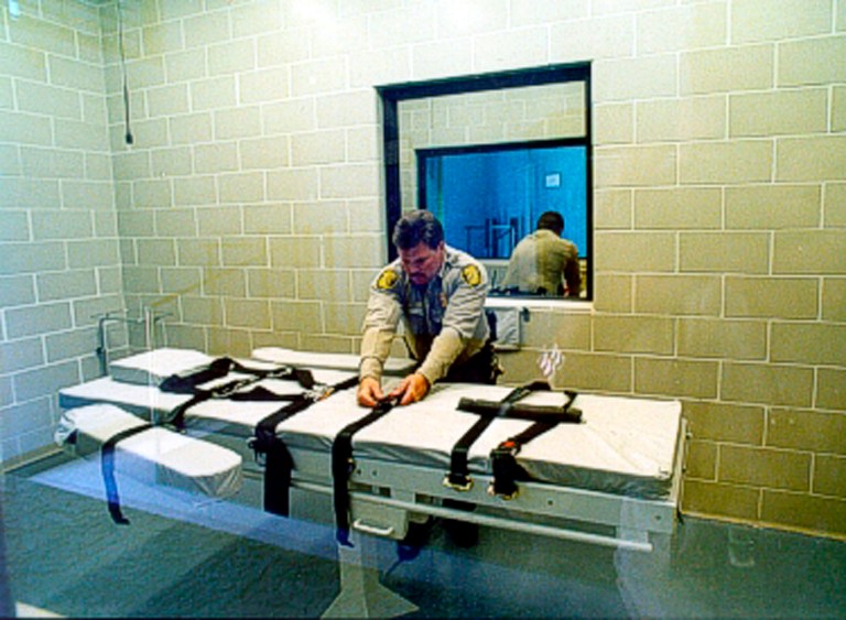 An unidentified Arizona state prison guard adjusts the straps on the gurney used for lethal injections at the Arizona State Prison at Florence in this undated photo provided by the Arizona Department of Corrections. (AP Photo/Arizona Department of Corrections)