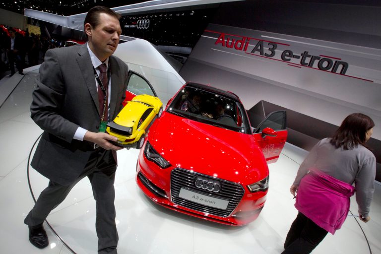 FILE - In this April 20, 2014 file photo, a man holds a scaled model of a Audi car as he walks past the Audi A3 e-tron displayed at the China Auto show in Beijing, China. China on Thursday, Sept. 11, 2014, announced it will fine automaker Audi $40.5 million and Chrysler $5.2 million in a sweeping anti-monopoly probe of their industry that has prompted complaints foreign businesses are being treated unfairly. (AP Photo/Ng Han Guan, File)