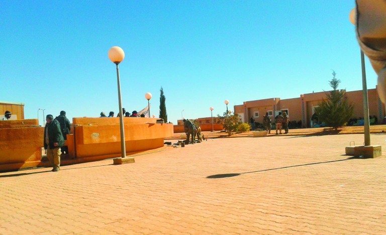 In this Jan. 16, 2013 photo secretly taken by a hostage, three Islamic militants, rear right, stand in front of foreigners that were taken hostage, in front of the building in the background, as Algerians, left, who are allowed to move, stand outside the living quarters of the Ain Amenas natural gas complex in Ain Amenas, Algeria. (AP Photo/Kyodo News) JAPAN OUT, MANDATORY CREDIT, NO LICENSING IN CHINA, HONG KONG, JAPAN, SOUTH KOREA AND FRANCE