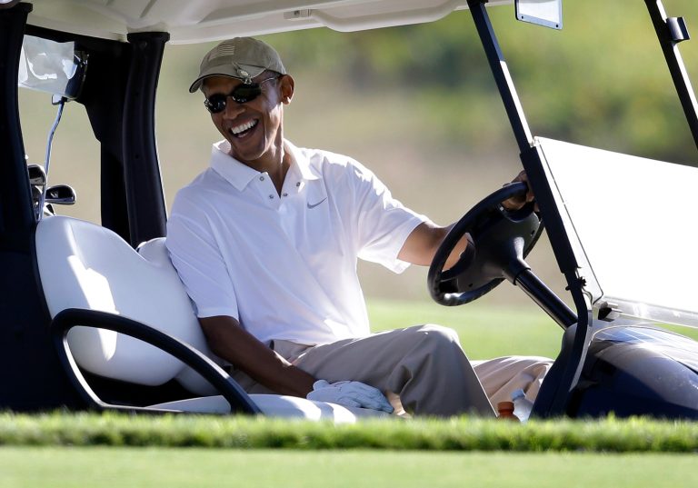 This Aug. 20, 2014 file photo shows President Barack Obama smiling at the wheel of a golf cart during golfing at Vineyard Golf Club in Edgartown, Mass., on the island of Martha's Vineyard. (AP Photo/Steven Senne, File)