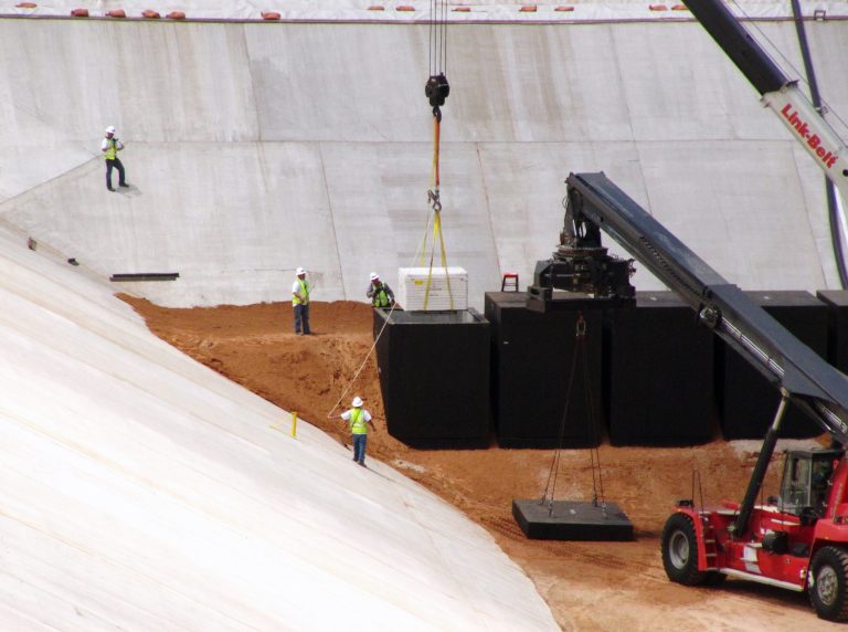 FILE - In this June 6, 2013 file photo, crews from Waste Control Specialists load the first of two containers with low-level radioactive waste from Los Alamos National Laboratory in New Mexico, into a reinforced 8-inch-thick concrete container at the 90-acre federal dump where it will remain forever, near Andrews, Texas. Regulators have approved allowing depleted uranium to be buried at a West Texas nuclear waste dump site. (AP Photo/Betsy Blaney, File)