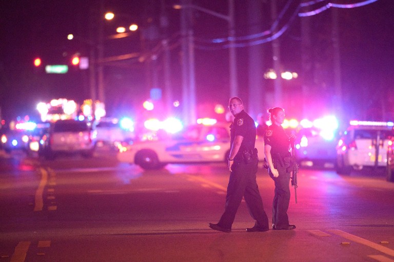 Police officers stand guard down the street from the scene of a shooting involving multiple fatalities at a nightclub in Orlando, Fla., Sunday, June 12, 2016. (AP Photo/Phelan M. Ebenhack)