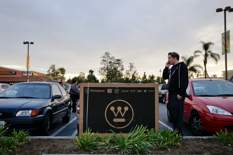 FILE - In this Thursday, Nov. 28, 2013, file photo, Robert McCormick, 23, whose car is not big enough for a 60-inch HDTV he purchased from a Kmart store, talks on the phone while waiting for his father-in-law to bring his pickup truck in Anaheim, Calif. The Commerce Department releases the report on durable goods for November, on Tuesday, Dec. 24, 2013. (AP Photo/Jae C. Hong, File)