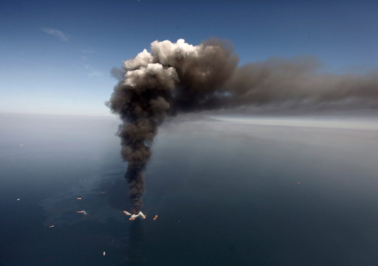 FILE -  In this Wednesday, April 21, 2010 file photo, oil can be seen in the Gulf of Mexico, more than 50 miles southeast of Venice on Louisiana's tip, as a large plume of smoke rises from fires on BP's Deepwater Horizon offshore oil rig. A federal appeals court on Monday, May 19, 2014, refused to reconsider its previous ruling that businesses don't have to prove they were directly harmed by BP's 2010 Gulf Of Mexico oil spill to collect settlement payments. (AP Photo/Gerald Herbert, File)