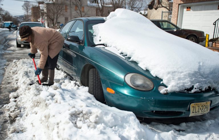 Ingrid Parham chisels away at frozen snow surrounding her car, Sunday, Feb. 16, 2014, in Paterson, N.J., on in preparation for work on Monday. (AP Photo/Northjersey.com, Amy Newman) ONLINE OUT; MAGS OUT; TV OUT; INTERNET OUT;  NO ARCHIVING; MANDATORY CREDIT.