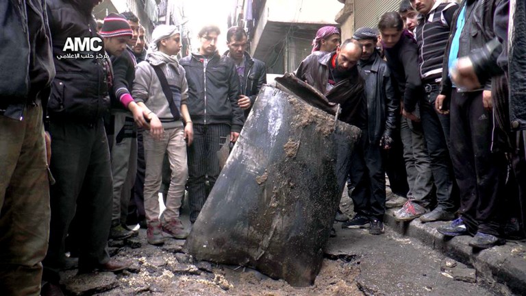 FILE - In this Sunday, Jan. 19, 2014, file photo provided by Aleppo Media Center (AMC), an anti-Bashar Assad activist group, which has been authenticated based on its contents and other AP reporting, Syrian citizens inspect an unexploded barrel of explosives which was dropped from a Syrian forces helicopter, on a street in Aleppo, Syria. For nearly two months, the Syrian government has conducted an intense air campaign on opposition-held districts of the northern city of Aleppo. Airstrikes on the city over the past week alone have killed some 245 people, according to activists. That pace rivals a two-week stretch in the second half of December when more than 500 people were killed in Aleppo airstrikes. (AP Photo/Aleppo Media Center, AMC, File)