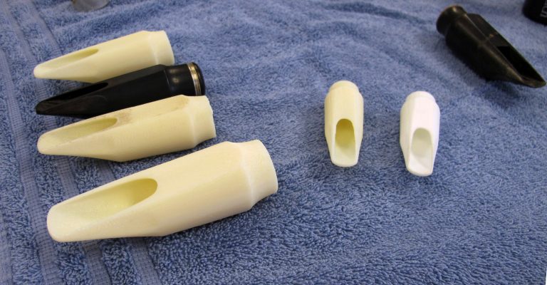 In this July 17, 2014 photo, an original mouthpiece for a 19th-century saxophone built by Adolphe Sax, second from top left, sits among 3D copies on at the University of Connecticut's Depot campus in Mansfiled, Conn. UConn researchers are using CT scans and 3D printing to help study and restore antique musical instruments. (AP Photo/ Pat Eaton-Robb)