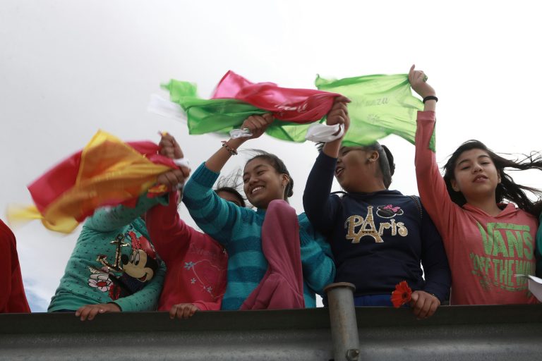 Young people wave colored flags reading 