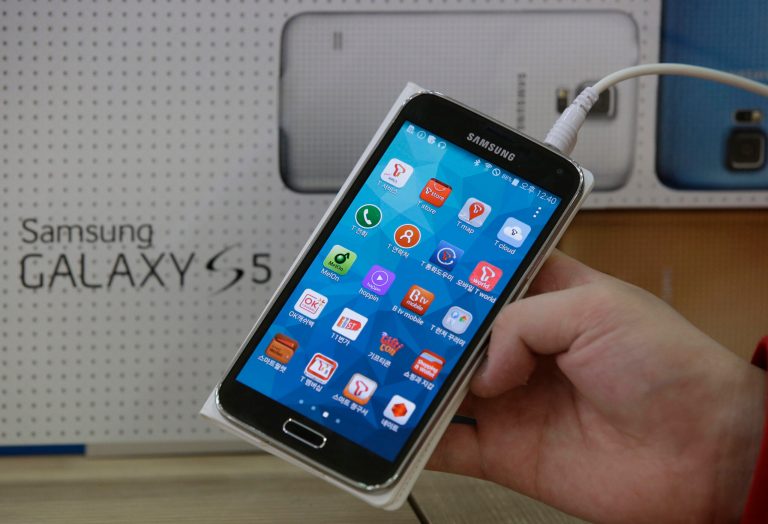 FILE - In this March 27, 2014 file photo, an employee shows Samsung's Galaxy S5 smartphone at a mobile phone shop in Seoul, South Korea. The high-stakes battle between the world's largest smartphone makers is scheduled to wrap up this week after a monthlong trial that has pulled the curtain back on just how very cutthroat the competition is between Apple and Samsung. Closing arguments in the patent-infringement case are scheduled to begin Monday, April 28 with the two tech giants accusing each other, once again, of ripping off designs and features. At stake: $2 billion if Samsung loses, a few hundred million if Apple loses. (AP Photo/Lee Jin-man, File)