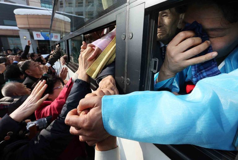 An unidentified North Korean woman on a bus weeps as she holds her South Korean relative's hand after the Separated Family Reunion Meeting at Diamond Mountain in North Korea, Tuesday, Feb. 25, 2014.  The first reunions of North and South Koreans in more than three years have been held in North Korea. The final group of Koreans to participate in reunions ends Tuesday. (AP Photo/Yonhap, Lee Ji-eun)  KOREA OUT