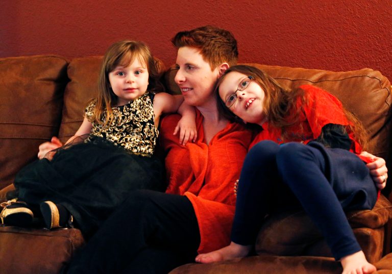 In this Jan. 17, 2014 photo, melanoma survivor Jodi Duke, center, sits with her daughters Zoe, left, 3, and Violet, 8, at home in Aurora, Colo. (AP/Brennan Linsley)