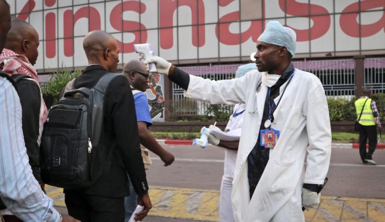 In this photo taken on June 2, 2018, a health worker checks people's temperatures as they disembark a plane at the airport in Kinshasa, Congo.
