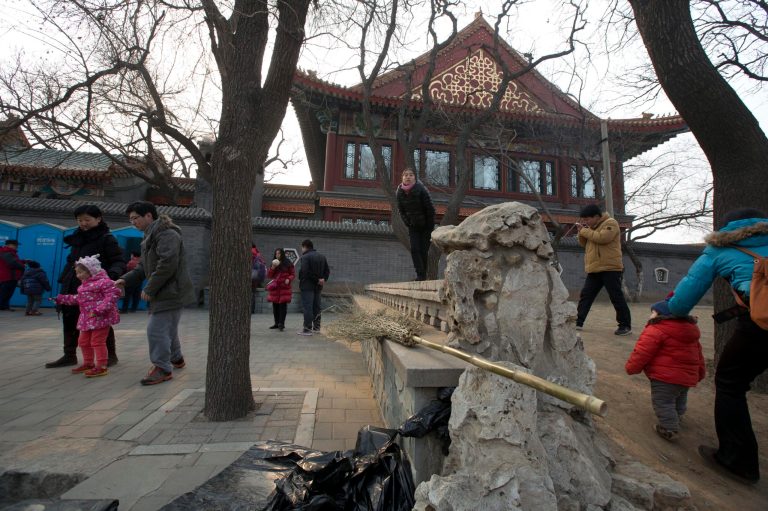 Visitors to a park walk outside the walls of the Scholarly House restaurant in Beijing, China, Wednesday, Feb. 5, 2014.  For years, the sumptuous Scholarly House restaurant and its compound of pavilions in the center of Beijing's Dragon Lake Park has been off-limits to most park goers, catering to wealthy businessmen and government officials. (AP Photo/Ng Han Guan)