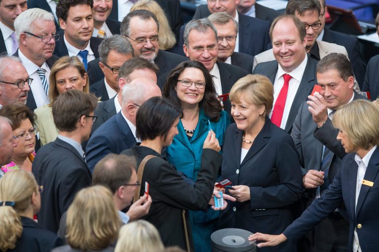 German chancellor  Angela Merkel, center right,  stands next to  labor minister Andrea Nahles,  center left, as they are surrounded by parliamentarians casting  their vote  in the German parliament, Bundestag, in Berlin Thursday July 3, 2014. The German Parliament has approved the introduction of the country's first national minimum wage, which will guarantee most workers in Europe's biggest economy at least 8.50 euros (US $11.60) per hour starting next year.  (AP Photo/dpa, Maurizio Gambarini)