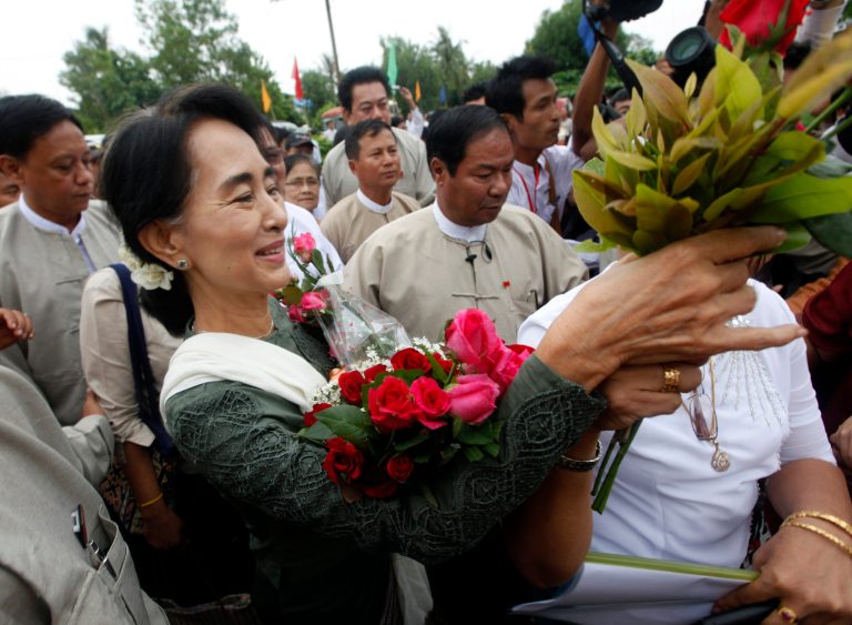   FILE - In this July 27, 2013, file photo, Myanmar opposition leader Aung San Suu Kyi receives flowers from her supporters upon arrival to attend the opening ceremony of a central library at Kaw Hmu township in Yangon, Myanmar. The Obama administration wants to restart U.S. defense training for Myanmar that was cut 25 years ago after a bloody crackdown on protesters. With the backing of opposition leader Aung San Suu Kyi, U.S. defense legal experts last week made their second trip to Myanmar in two months, scoping out what help they can provide on teaching about human rights and rule of law. (AP Photo/Khin Maung Win, File)  