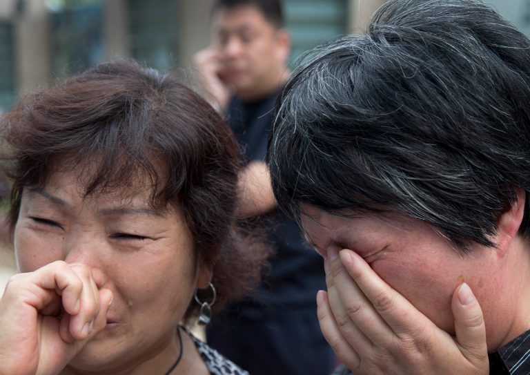 Chinese relatives of passengers onboard the missing Malaysia Airlines Flight 370 cry outside the airlines' office after officials from the airline refused to meet with them in Beijing, China Wednesday, June 11, 2014. Despite a massive air and sea search, no trace of Flight 370 has been found, three months after it vanished after taking off from Kuala Lumpur bound for Beijing. (AP Photo/Andy Wong)