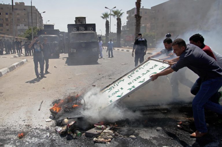Men try to clear burning debris out of a street after clashes between Egypt's security forces and supporters of ousted President Mohammed Morsi in Cairo's twin city of Giza, Egypt, Friday, July 4, 2014. A bomb accidentally exploded on a farm Friday southwest of the Egyptian capital, killing at least three suspected militants who were handling it, a security official said. (AP Photo/Ahmed Abd el-Gwad, El Shorouk newspaper) EGYPT OUT